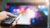 Young man holding television remote control. Hands pointing to tv screen set and turning it on or off select channel watching tv 